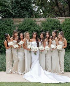 a group of women standing next to each other in front of some bushes and flowers