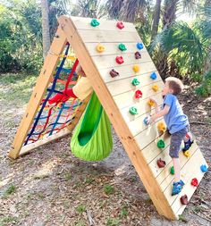 a young boy climbing up the side of a wooden climbing wall