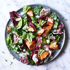 a plate full of salad on a marble table top with the words, lettuce and croutons