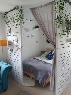 a bedroom with white walls and plants growing on the side of the wall above the bed