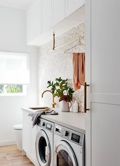 a washer and dryer in a white laundry room with wood flooring next to a window