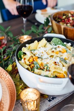 a close up of a bowl of food on a table with plates and wine glasses