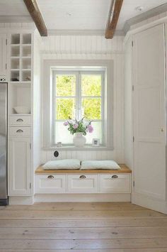 a kitchen with white cabinets and wood flooring next to an open refrigerator freezer