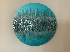 a blue and silver wall hanging on the side of a white wall with lots of beads