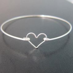 Sterling Silver Heart Bangle Bracelet - A sterling silver heart charm has been transformed into a dainty & delicate heart bracelet with a sterling silver bangle band for you to wear or gift. This is the perfectly dainty heart bracelet for a Valentine's Day gift. Or if you need bridesmaid wedding jewelry and have been looking for sterling silver heart bracelets for bridesmaids, these make for cute bridesmaid gift bracelets. This sterling silver heart jewelry looks great together with others f Adjustable Silver Heart Bangle Bracelet, Delicate Adjustable Heart Bracelet For Anniversary, Adjustable Heart Charm Bangle Bracelet, Dainty Sterling Silver Charm Bracelet With Heart Charm, Silver Heart-shaped Nickel-free Bracelet, Adjustable Heart-shaped Sterling Silver Bracelet, Sterling Silver Bangle With Heart Charm, Silver Nickel Free Heart Bracelet, Silver Heart Charm Bracelet Adjustable