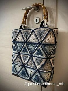 a blue and white crocheted bag hanging from a hook on a door handle