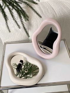 a mirror sitting on top of a table next to a plant