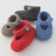 four knitted baby shoes with buttons on them