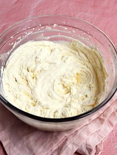 a glass bowl filled with batter on top of a pink cloth