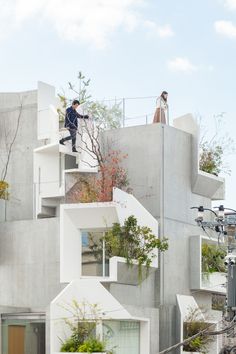 two people standing on the top of a building with stairs and balconies in front of them