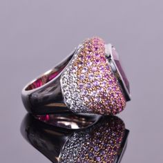 A gorgeous 12.21 carat trillion cut rubellite that is surrounded by an ombre of diamonds and pink sapphires. Made of 5.65 carats of delicate pink sapphires and .62 carats of white diamonds, all are set in 18k gold. This statement ring is very unique and a real eye catcher. Ring size is a 7 and weighs 25.8 grams. Pink Sapphire, Cocktail Rings, Diamond White, Statement Rings, 18k Gold, Sapphire, Ring Size, Pink, Gold