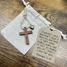 a small wooden cross with a bible verse on it sitting next to a drawstring bag