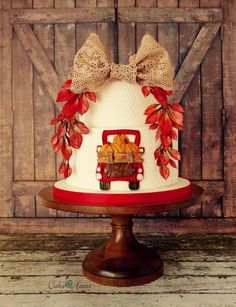 a wedding cake decorated with fall leaves and bows on a wooden table in front of a barn door