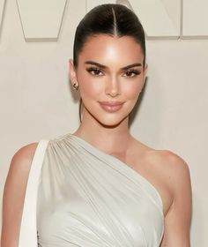 an image of a woman in a white dress posing for the camera with her hair pulled back