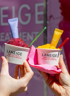 two people holding up ice cream cups with different flavors on them and one is pink