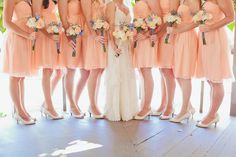 a group of women standing next to each other in front of a window holding bouquets