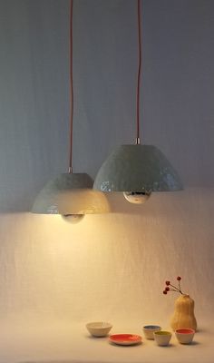 two lamps are hanging over bowls on a table