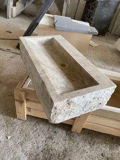 a large stone sink sitting on top of a wooden stand in a room filled with unfinished furniture