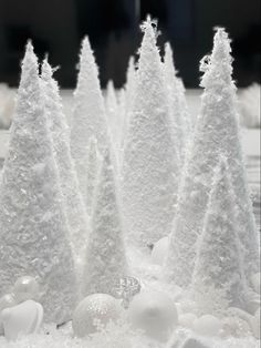 small white trees are in the snow with balls and ornaments around them, as if for christmas or new year's eve