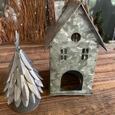 a metal bird house next to a silver tree ornament on a wooden table