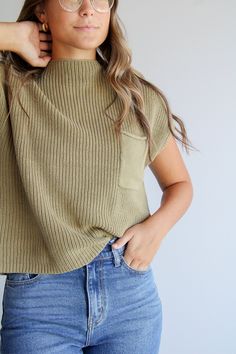 Stay cozy in this best-selling Prague Mock Neck Top! Crafted with organic cotton, it features a slouchy fit with a pocket. Its olive hue will be a stylish addition to your wardrobe. Experience this highly awaited restock—get yours now! How to style: Pair with your favorite pair of jeans for a relaxed yet cool girl vibe. About the product Olive in color Slouchy fit Pocket Mock Neck Knitted material 100% cotton Fall Everyday Tops With Pockets, Everyday Fall Tops With Pockets, Casual Olive Tops For Winter, Cozy Green Top For Everyday, Green Tops With Side Pockets For Fall, Casual Green Top With Side Pockets, Cozy Crew Neck Tops With Pockets, Casual Green Tops With Side Pockets, Cozy Tops With Side Pockets For Fall