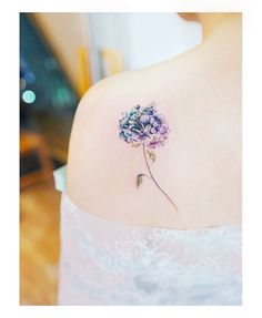 a flower tattoo on the back of a woman's upper arm, which is covered in purple and blue flowers