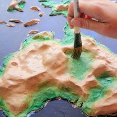 someone is painting the map of australia with green and brown paint