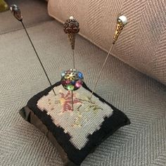 two pins sticking out of a cushion on the floor in front of a couch with a pillow