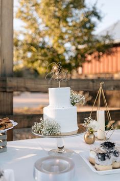 a white cake sitting on top of a table next to other desserts and pastries