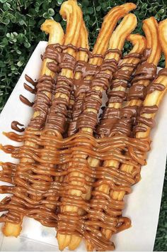 chocolate covered pretzels are stacked on top of each other in front of some bushes