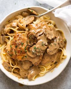 a white bowl filled with pasta covered in mushroom gravy and topped with a fork