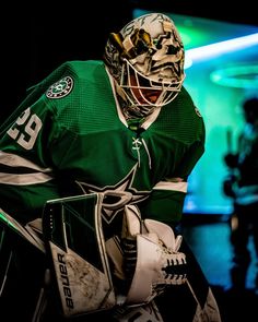 a hockey goalie in green and white uniform