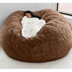 a woman laying on top of a bean bag chair in a room with white walls