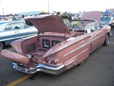 an old pink car parked in a parking lot