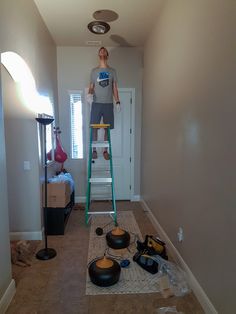 a man is standing on a ladder in the middle of a room with other items