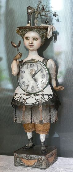 an antique clock with a woman holding a bird on it's head and wearing a hat