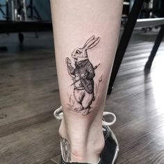 a tattoo on the leg of a woman with a rabbit holding a knife and fork