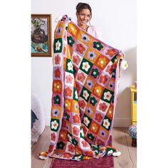 a woman is holding up a colorful blanket