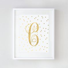 a gold foil print with the letter g in it's center on a white wall