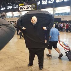 a man in a suit and tie is holding an umbrella over his head as people walk by