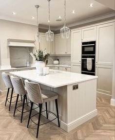 a large kitchen with an island in the middle and four bar stools around it