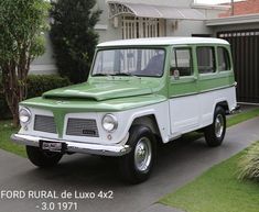 an old green and white truck parked in front of a house