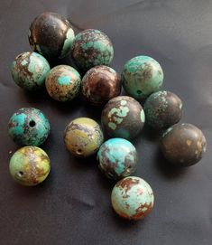 several different colored round beads on a black surface with brown and blue speckles