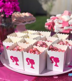 pink and white bags with silhouettes on them are sitting on a table in front of other desserts