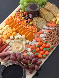 an assortment of cheeses, crackers, grapes and meats on a cutting board