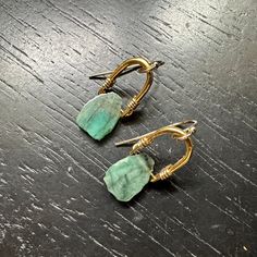 A beautiful Raw Emerald is suspended from one our tiny 24k gold bails with 14K Gold filled wire wraps and earwires. This combo of the bright gold and deep greens looks so great together! We've been up-leveling some 永 designs by adding a thick electroplating of 24K gold over our cast brass medallions- this combo allows for all the beauty and durability of the Gold finish while being much a more affordable option than solid cast gold! Emerald derives it’s glorious green color from the presence of Mod Earrings, Raw Emerald, Jewellery Showroom, Sacred Stones, Wholesale Gifts, Gold And Silver Rings, Feather Necklaces, Bright Gold, Herkimer Diamond