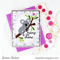 a handmade card with a koala bear on a tree branch and beads around it