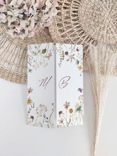 two cards with flowers on them sitting next to a wicker basket