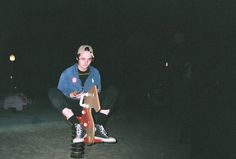 a man kneeling down on top of a skateboard