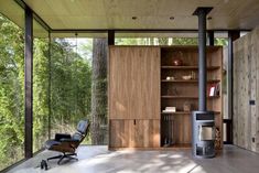 an empty chair in the middle of a room with wood paneling and glass walls